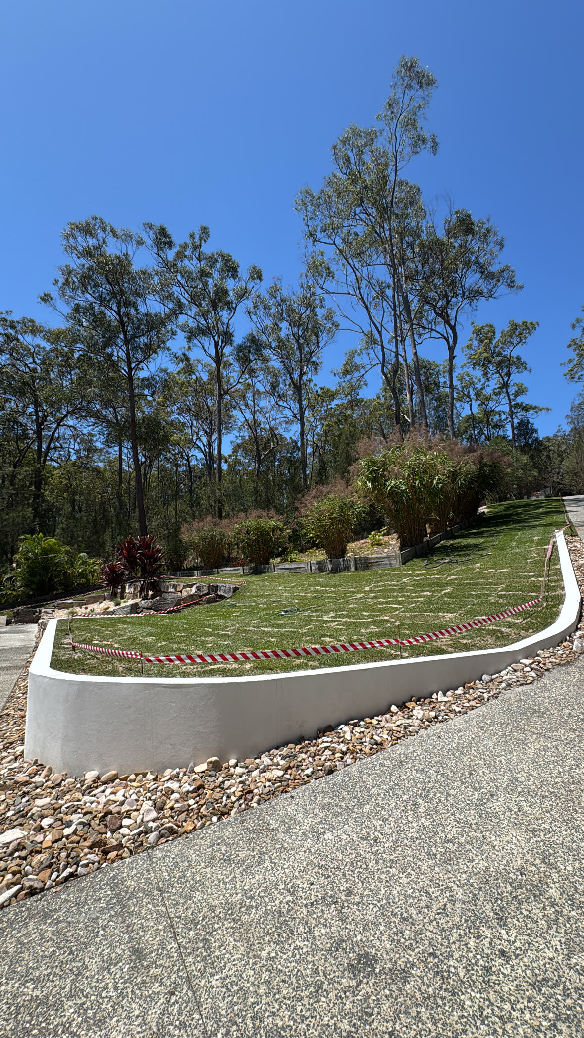 Fresh turf terraces behind a curved rendered wall